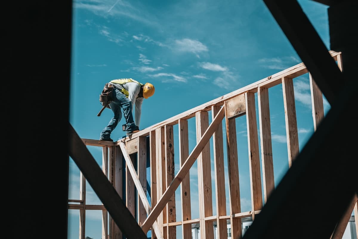 Carpenter framing a new home against a blue sky